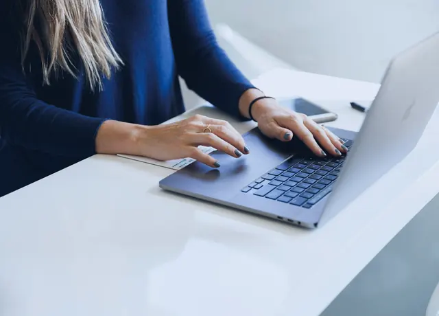 Hands typing on a laptop keyboard